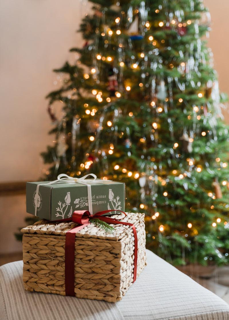 Santa Barbara Company Holiday Gift Baskets in front of a Christmas tree